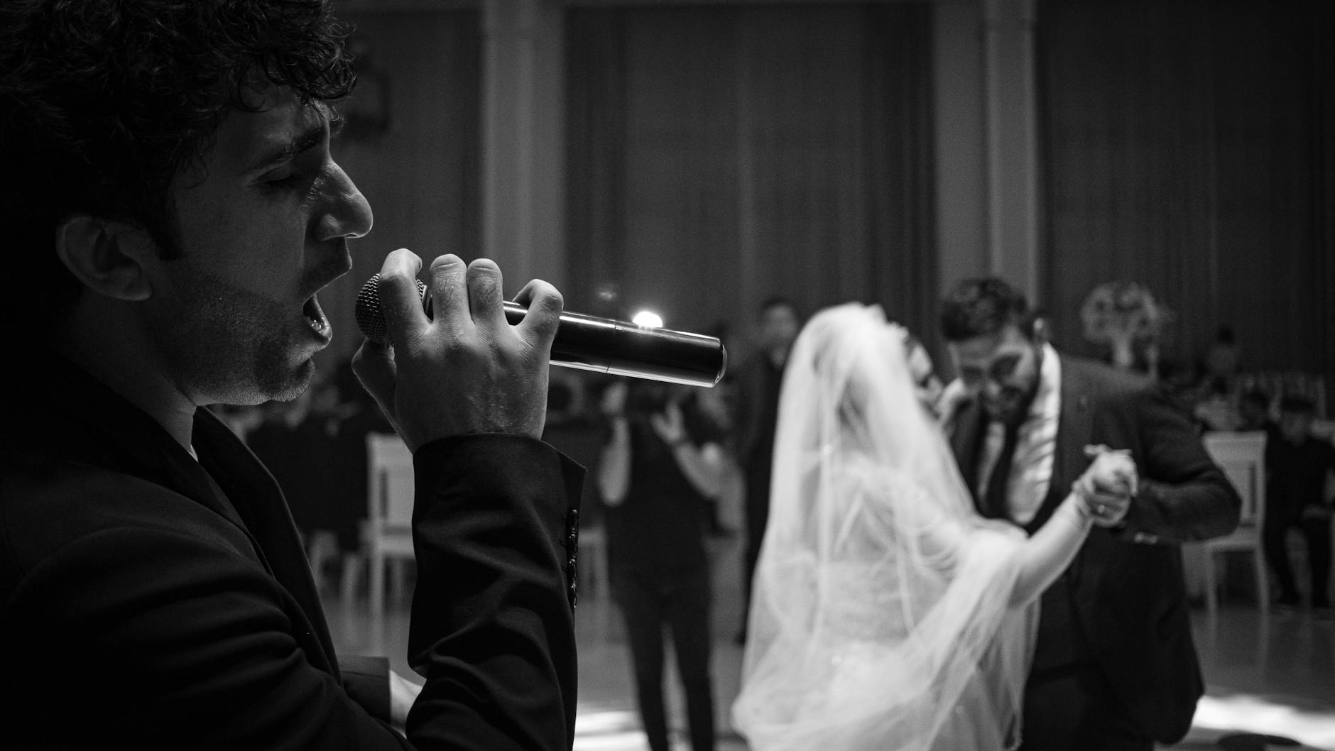 wedding singer and newlyweds dancing behind